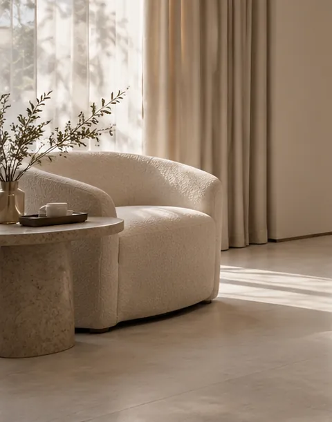 Poltrona clara e mesa lateral junto à janela com cortinas de linho