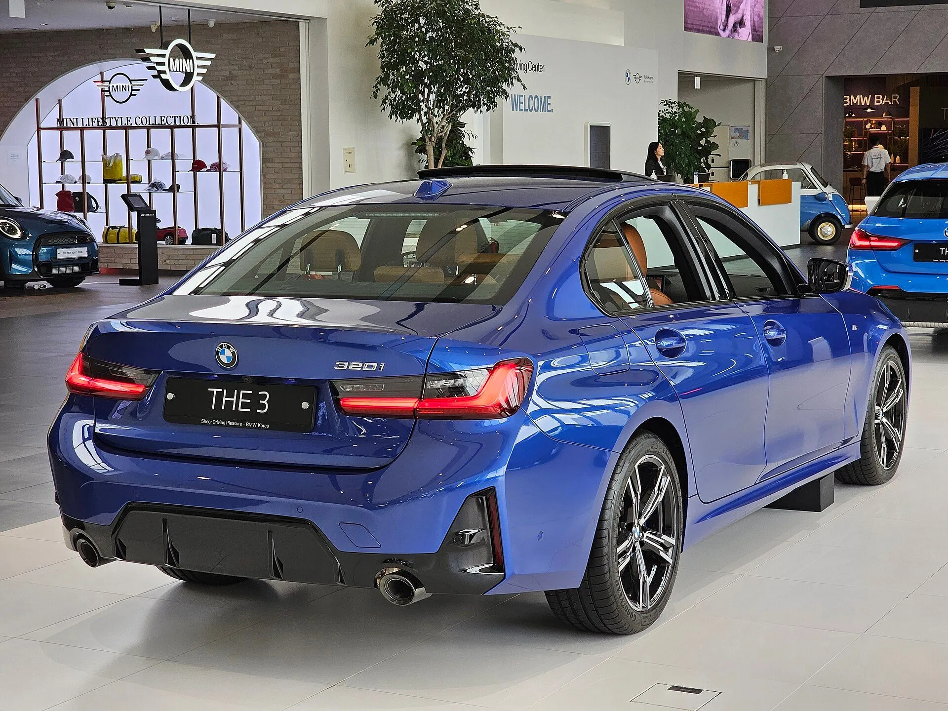 Traseira três-quartos do BMW 320i M Sport azul em showroom